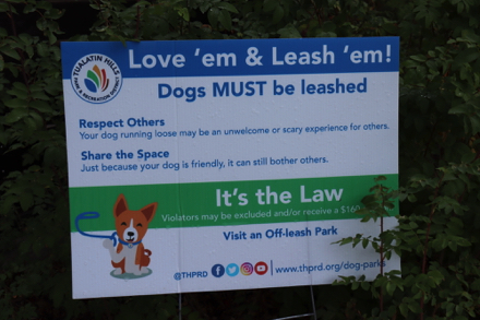 Dogs must be on leash — sign says: Love’em & Leash’em!